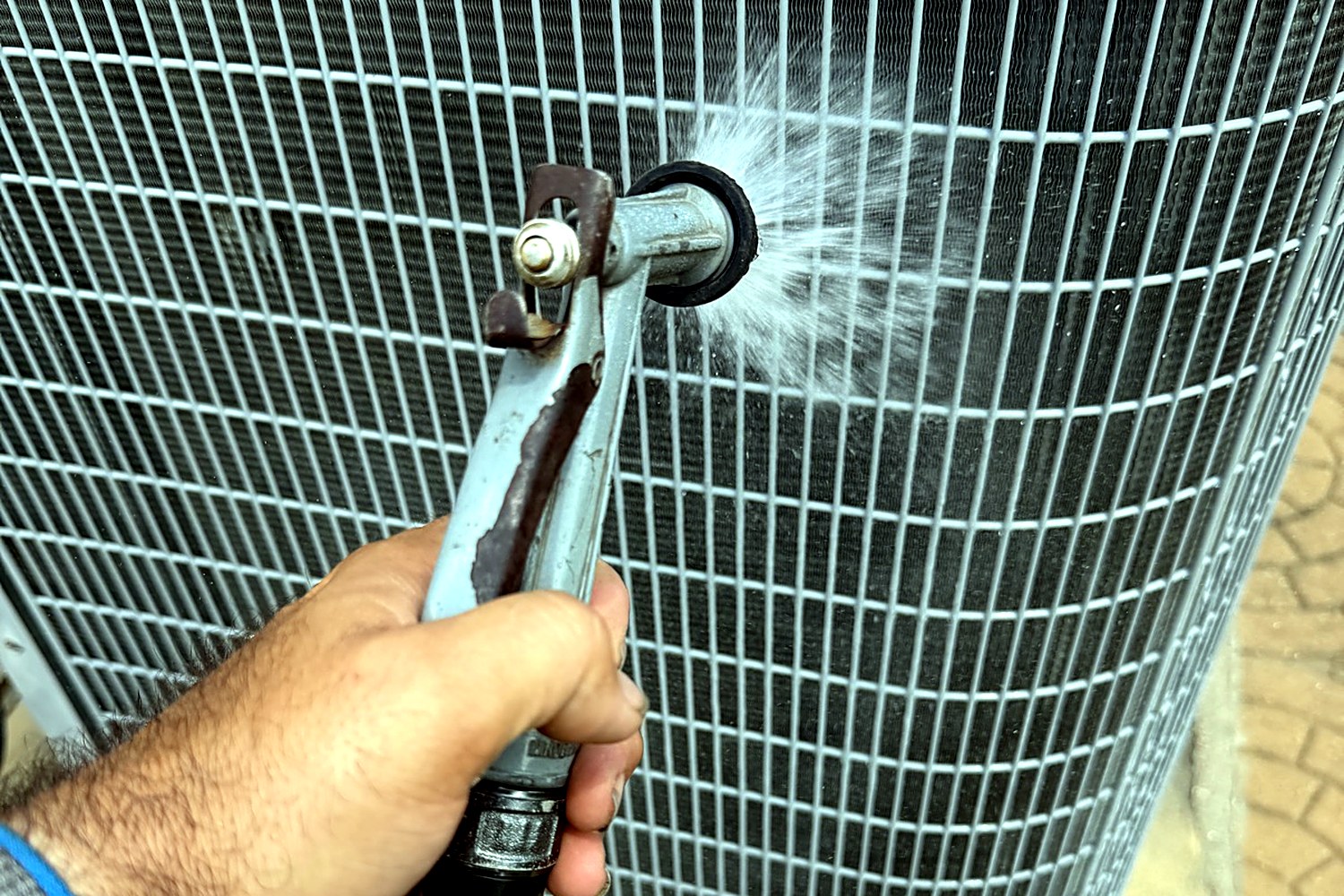 Technician washing a condenser coil during an AC tune-up in Houston