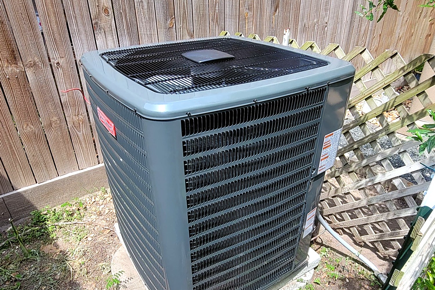 Goodman condenser installed by a fence at a Houston home